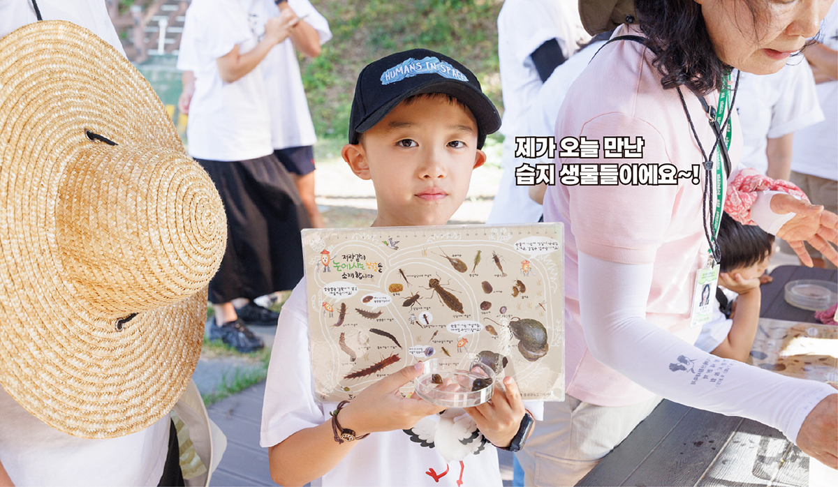 습지에서 만난 생물을 관찰하는 아이